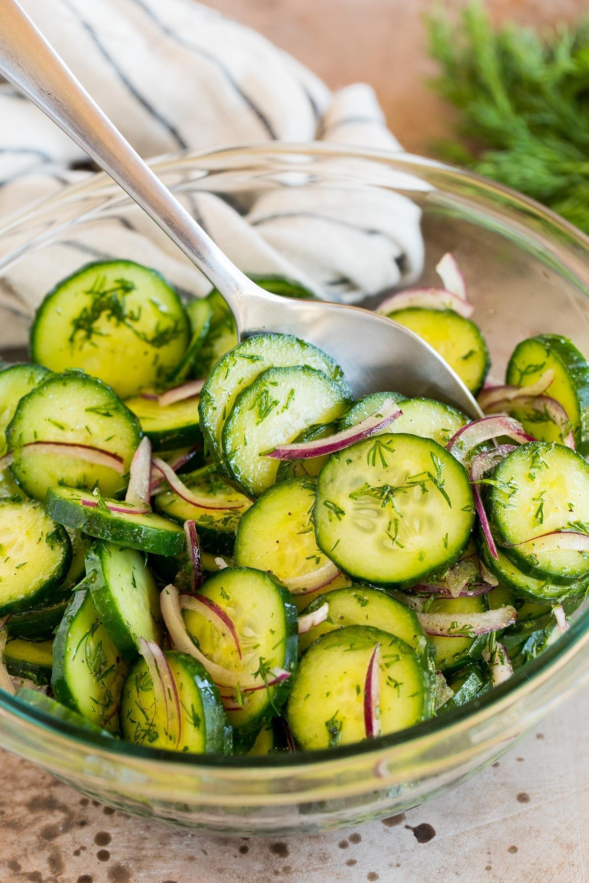Ein Teller Gurken-Dill-Salat mit einem Löffel darin.