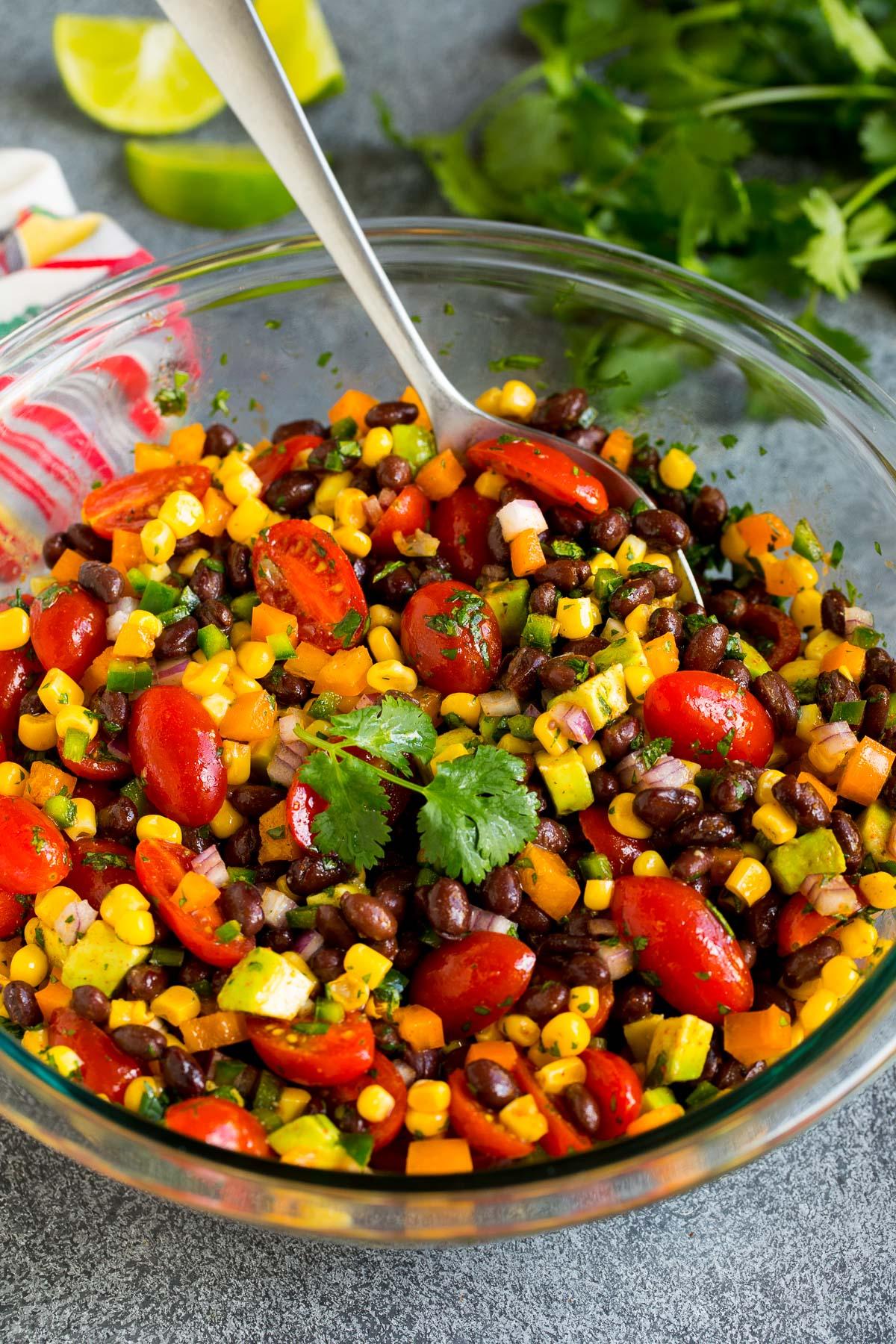 Eine Schüssel mit schwarzem Bohnensalat und einem Servierlöffel darin.