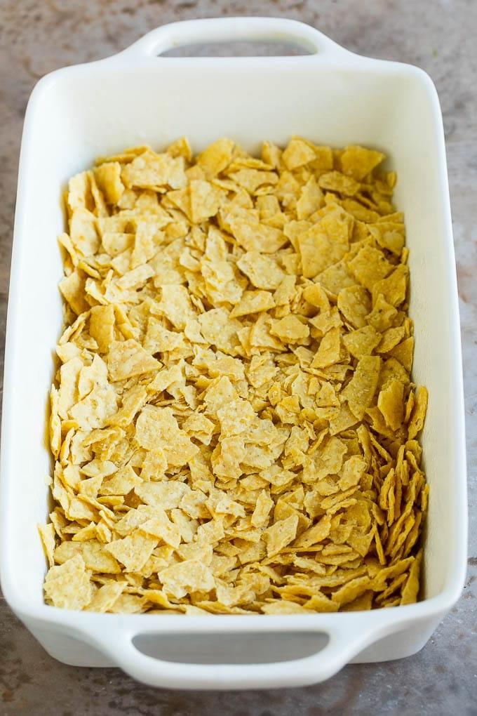 Zerstoßene Tortilla Chips in einer Auflaufform ausgelegt.