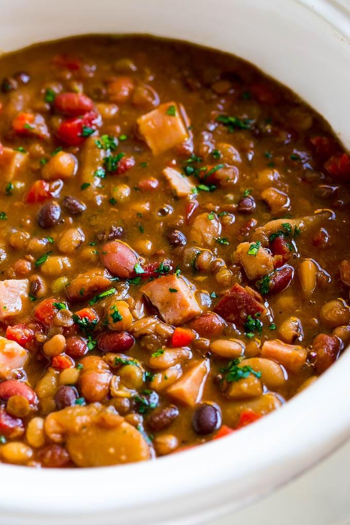 Schinkenknochensuppe Slow Cooker | Schinken-Bohnen-Suppe | Schinkenknochen-Bohnen-Suppe | Schinkensuppe | Rezept für Schinkenreste #schinken #schinkensuppe #schinkenreste #suppe #slowcooker #crockpot #ahurt Ein Slow Cooker voll Suppe, mit Petersilie bestreut.