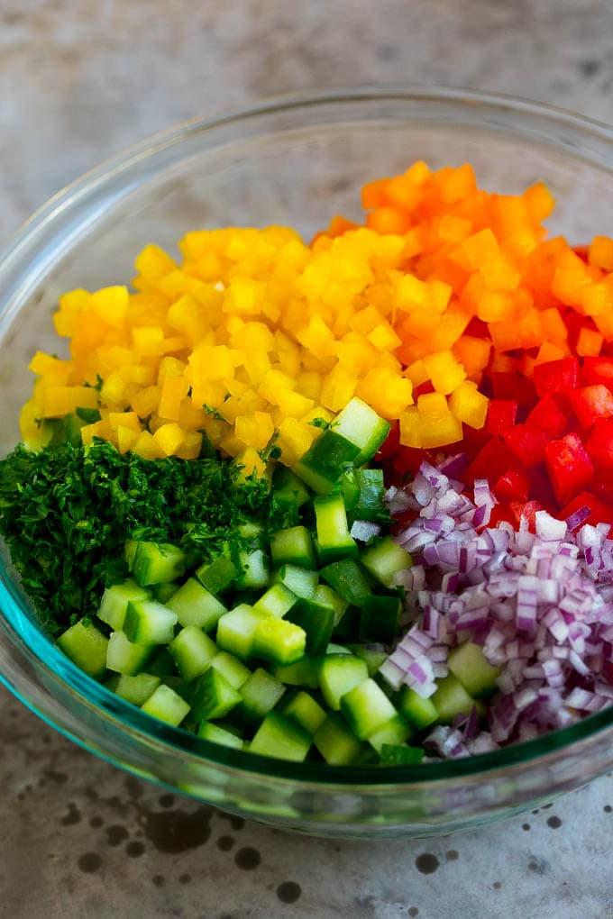 Israelischer Salat Rezept | Gurken-Salat | Tomaten-Salat | Gehackter Salat #salad #cleaneating #healthy #glutenfree #lowcarb #keto #sidedish #lunch #ahurt Gehackte Paprika, Gurken, Tomaten und Zwiebeln in einer Schüssel.