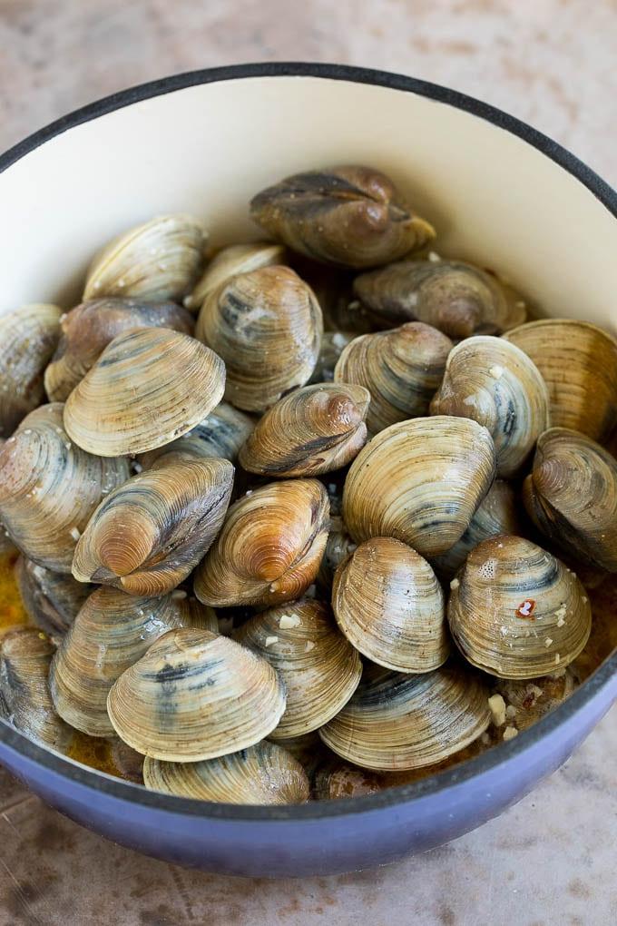 Venusmuscheln in einem Topf mit Butter und Weißwein, bereit zum Dämpfen.