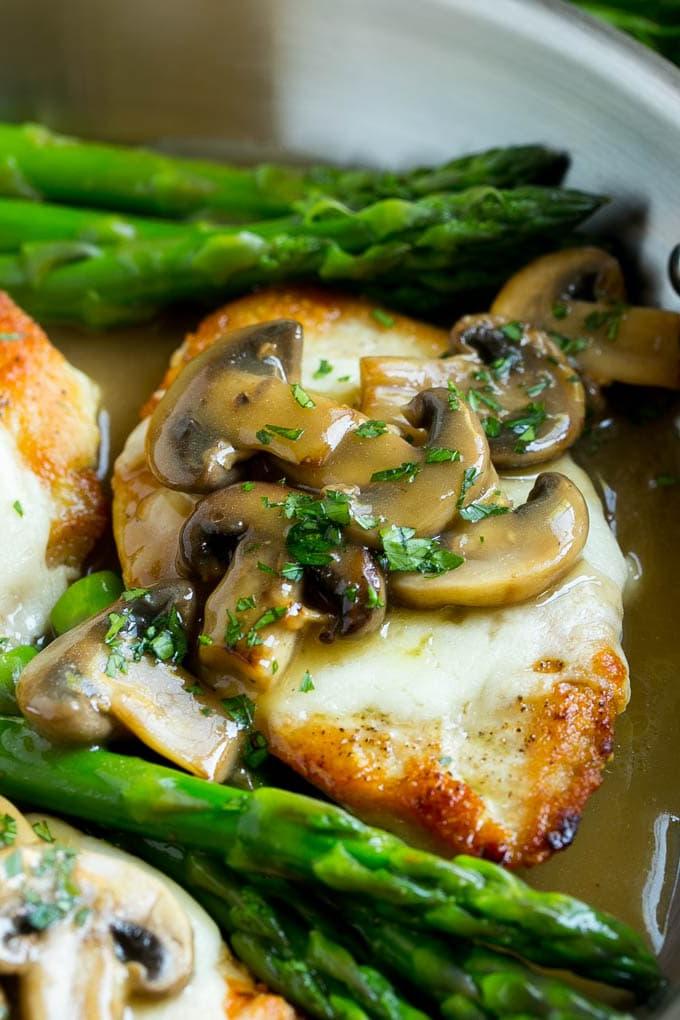 Eine Hähnchenbrust, bedeckt mit Mozzarella-Käse und Madeira-Pilzsauce in einer Pfanne.