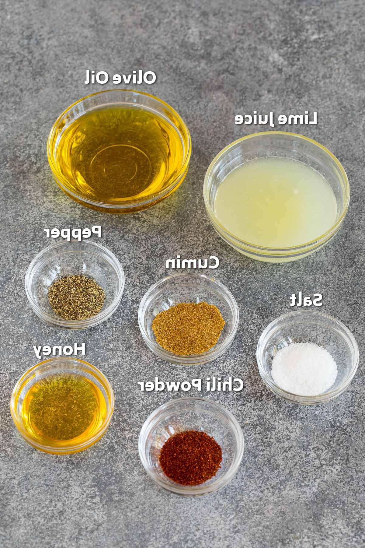 Schüsseln mit Zutaten für das Salatdressing, darunter Olivenöl, Limettensaft und Gewürze.