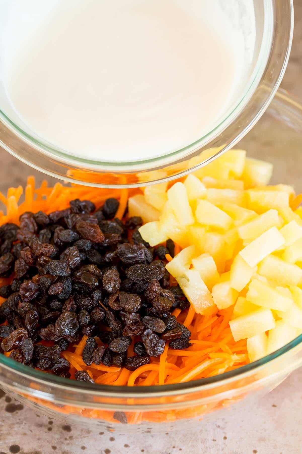 Karottensalat 5 Eine Schüssel Dressing wird über Karotten, Rosinen und Ananas gegossen.