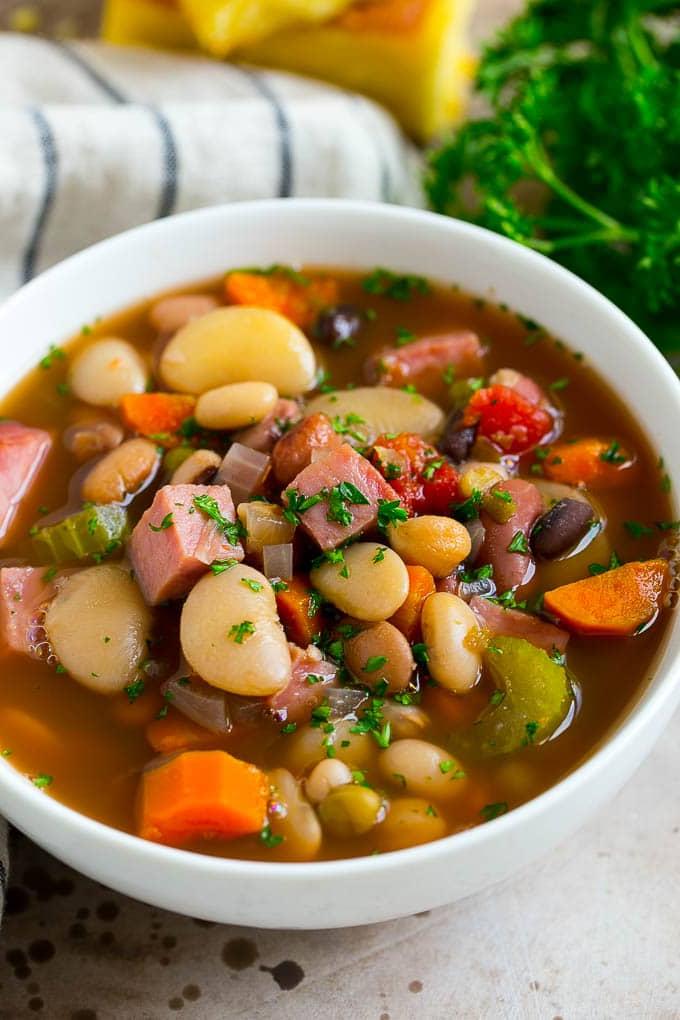 Schinken-Bohnen-Suppen-Rezept | Slow Cooker Schinken-Bohnen-Suppe | Crockpot Schinken-Bohnen-Suppe | Rezept für Schinkenreste #schinken #bohnen #suppe #slowcooker #crockpot #abendessen #abendessenimzoo Eine Schale Schinken-Bohnen-Suppe mit getrockneten Bohnen, Schinken und Gemüse, garniert mit frischer Petersilie.
