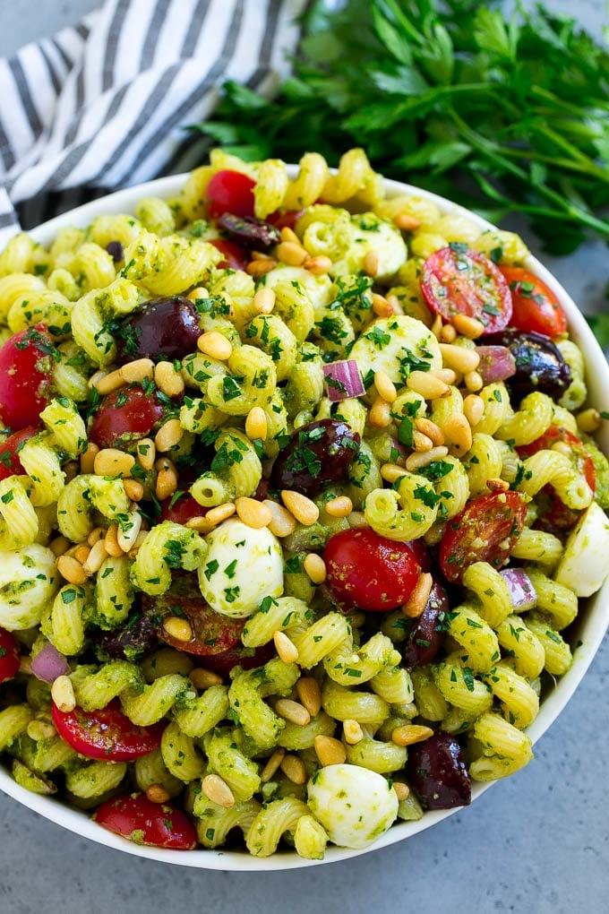 Pesto Nudelsalat | Italienischer Nudelsalat | Einfacher Nudelsalat #pasta #salad #pesto #olives #tomatoes #ahurt Eine Schüssel Pesto Nudelsalat, garniert mit Pinienkernen und gehackter Petersilie.