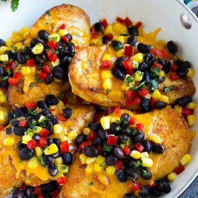 Hähnchen Santa Fe 2 Eine Pfanne mit Hähnchen Santa Fe, bestehend aus Hähnchenbrüsten, belegt mit geschmolzenem Cheddar, schwarzen Bohnen, Mais und roten Paprikawürfeln.
