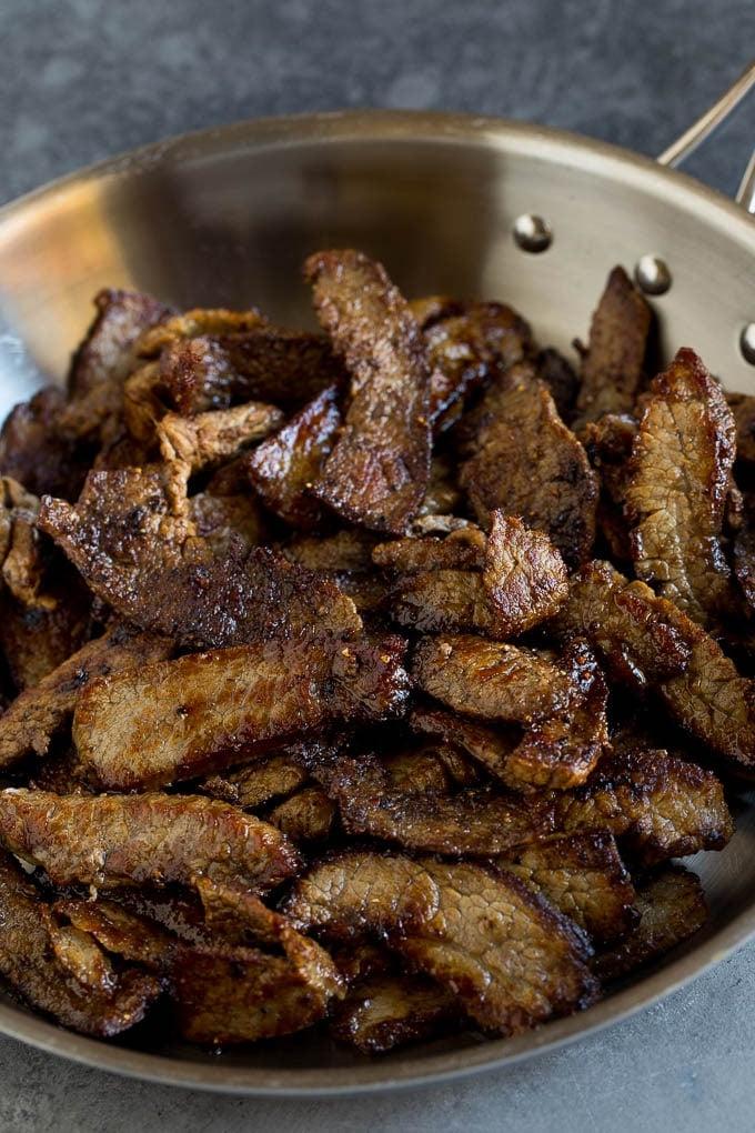 Dünne Scheiben angebratenen Flanksteaks in einer gusseisernen Pfanne.