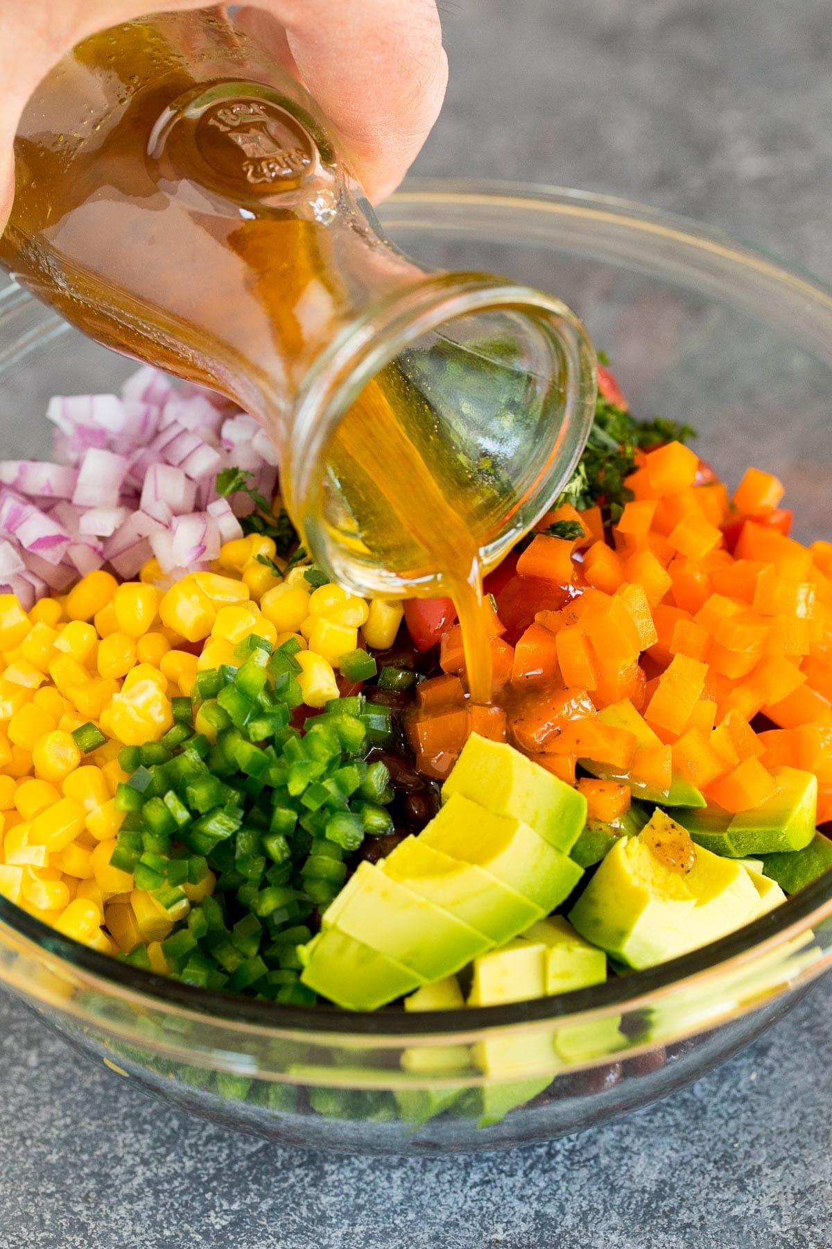 Dressing wird über einen Gemüse- und Bohnensalat gegossen.