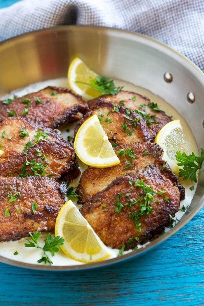 Scheiben von Schweine-Scallopini in einem Bett aus cremiger Soße mit Zitrone und Petersilie.