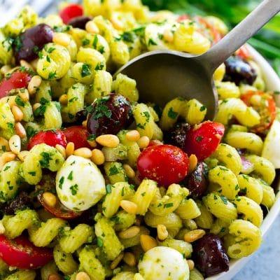 Pesto-Nudelsalat 2 Pesto Nudelsalat mit Kirschtomaten, Oliven, Mozzarella-Kugeln, Pinienkernen und roten Zwiebeln.