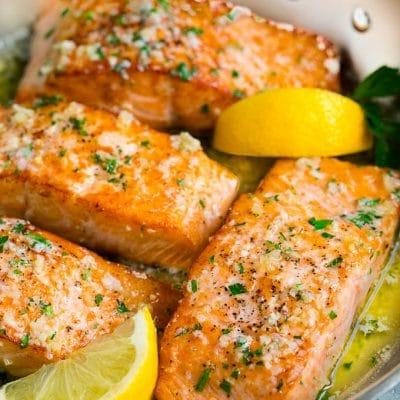 Pfannengebratener Lachs mit Knoblauchbutter 2 Pfannenlachsfilets in Knoblauchbuttersauce, detailliert und appetitlich angerichtet.