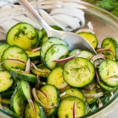 Ein Teller Gurken-Dill-Salat mit einem Löffel darin.
