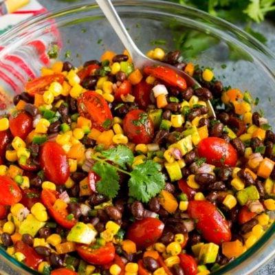 Eine Schüssel mit schwarzem Bohnensalat und einem Servierlöffel darin.