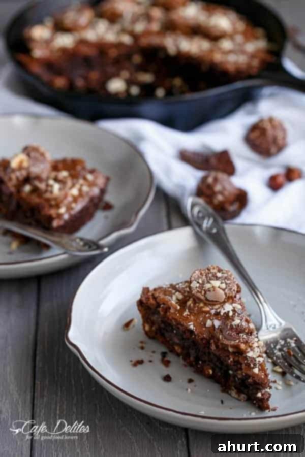 Ultimate Ferrero Rocher Skillet Brookie 2 A slice of Ferrero Rocher Deep Dish Skillet Brownie Cookie on a white plate, showcasing its gooey center and hazelnut topping.