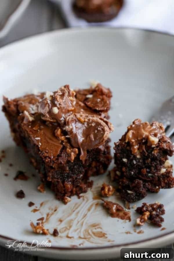 Ultimate Ferrero Rocher Skillet Brookie 3 A half-eaten Ferrero Rocher Deep Dish Skillet Brownie Cookie in a skillet, revealing layers of chocolate, Nutella, and hazelnuts.