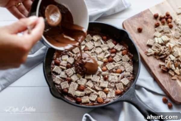 Ultimate Ferrero Rocher Skillet Brookie 7 Pouring melted Nutella over a layer of brownie cookie dough in a skillet, preparing the deep dish dessert.