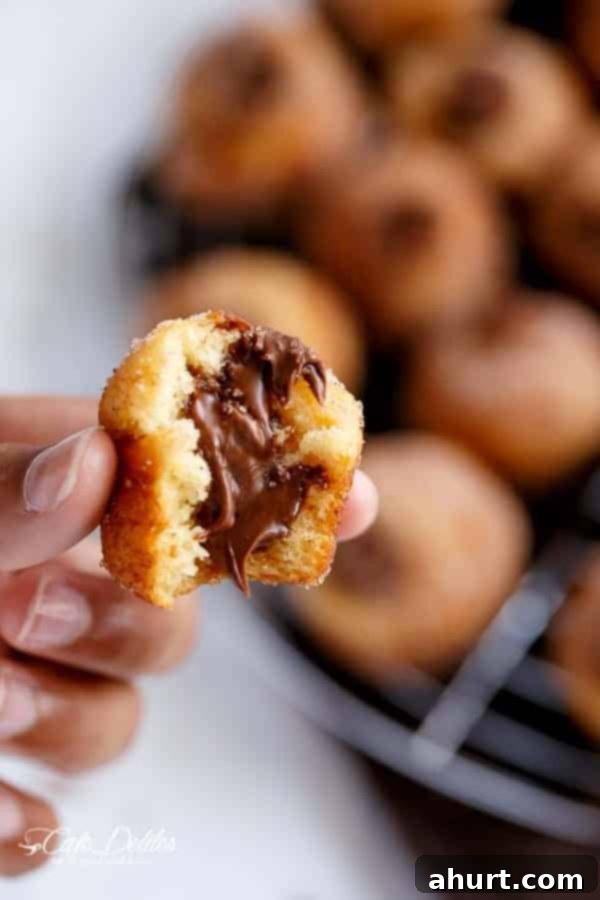 Churro Nutella Poppers 3 Nutella Churro Donut Holes with rich chocolate hazelnut cream oozing out from the middle, showcasing the generous filling.
