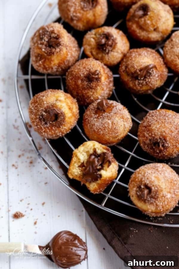 Churro Nutella Poppers 4 Freshly baked Nutella Churro Donut Holes cooling on a wire rack, ready for their buttery cinnamon sugar coating.
