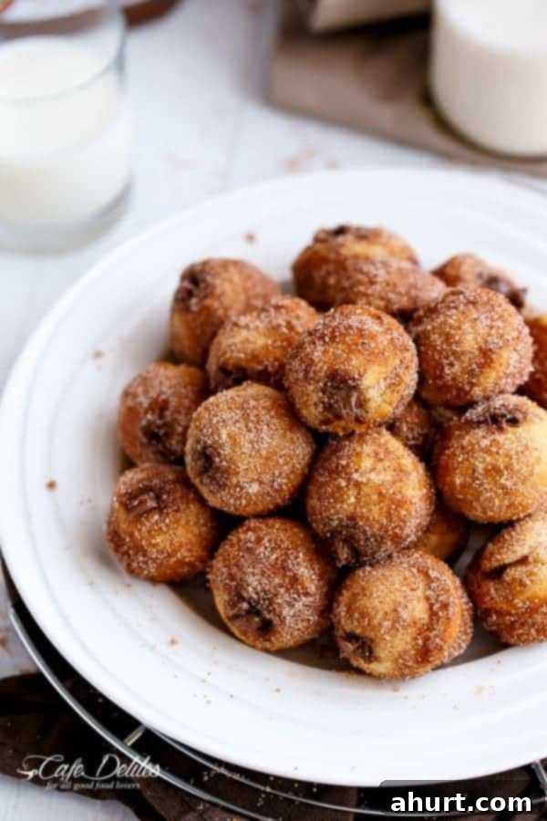 Churro Nutella Poppers 5 A plate piled high with golden Nutella Churro Donut Holes, showcasing their inviting texture and generous coating.