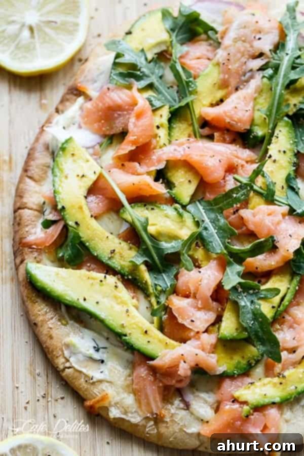 Half view of Smoked Salmon and Avocado Pizza on a pan from top, showcasing the fresh toppings and crispy crust.