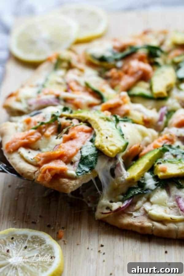 A slice taken out from Smoked Salmon and Avocado Pizza, showing the layers of salmon, avocado, and cream cheese base.