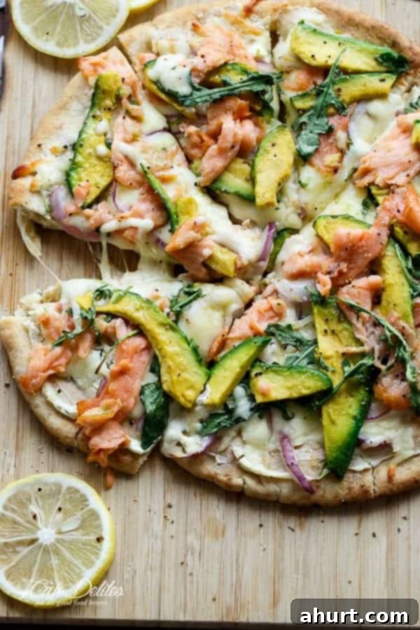 Smoked Salmon and Avocado Pizza being expertly cut into individual slices on a pan, ready to serve.