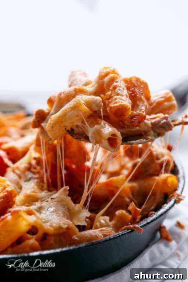 A spoon carrying some pasta from  Cheesy Chicken and Roasted Tomato Mozzarella Pasta Bake 