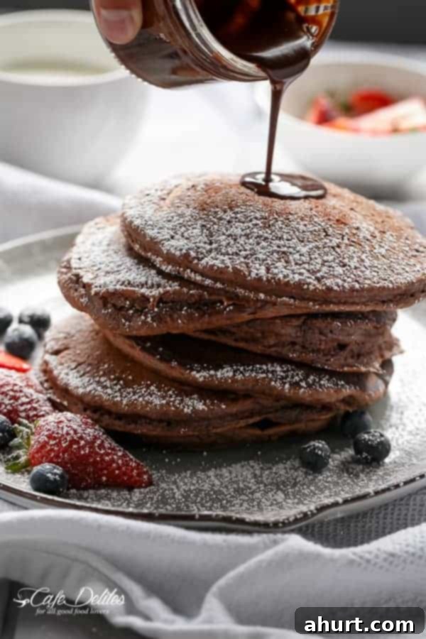 Chocolate sauce dripping over Double Chocolate Brownie Pancakes stack