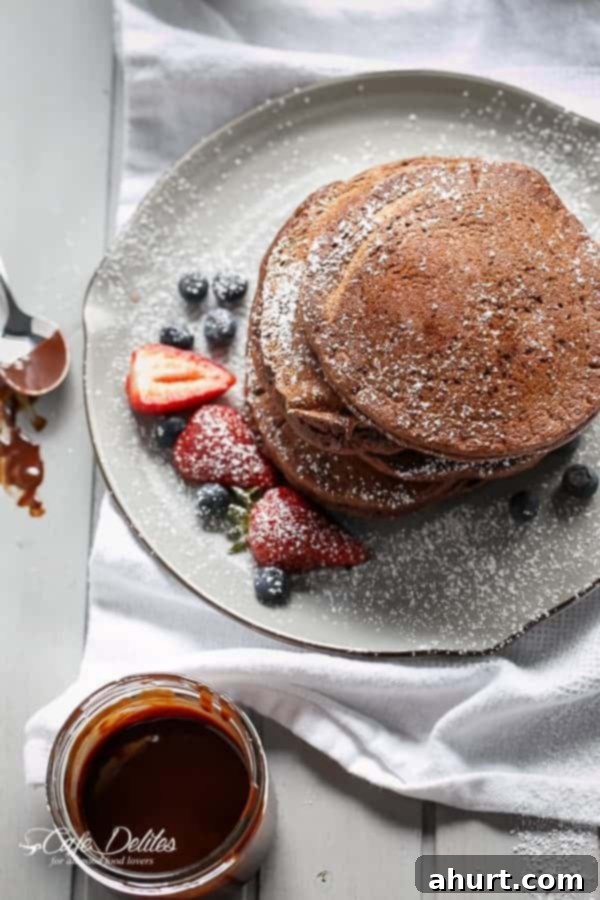 Top view image of Double Chocolate Brownie Pancakes with fresh strawberries and blueberries kept aside
