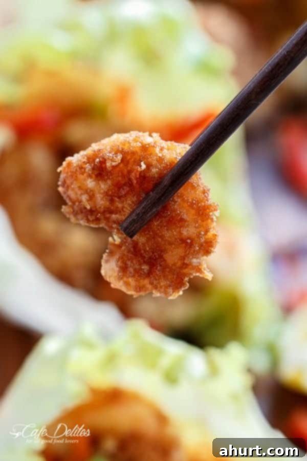 Crispy Oven-Fried Tempura Shrimp Lettuce Wraps with Teriyaki Sauce 5 An image focusing over a shrimp piece hold by chopsticks