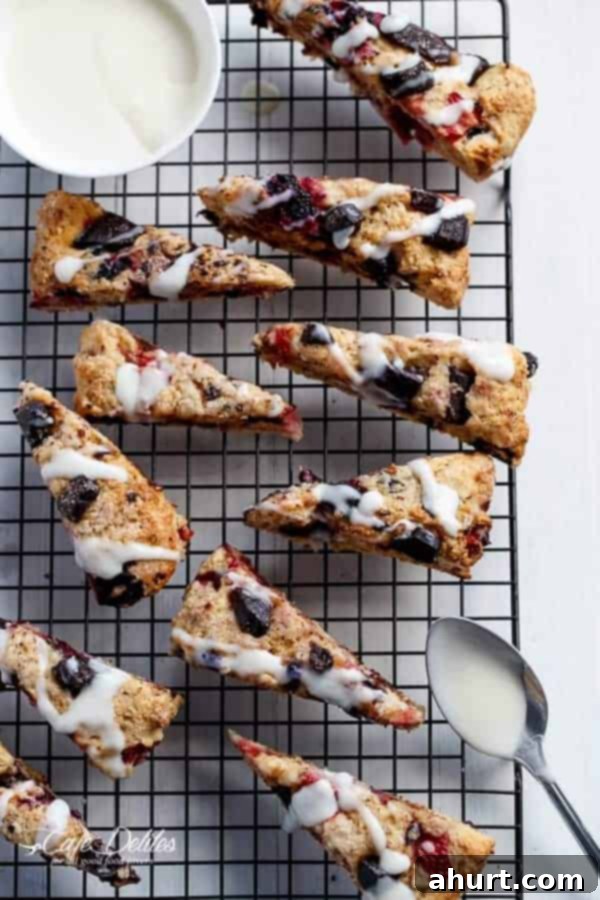 Mixed Berry and Chocolate Chunk Buttermilk Scones with a Cream Cheese Glaze resting on a cooling rack