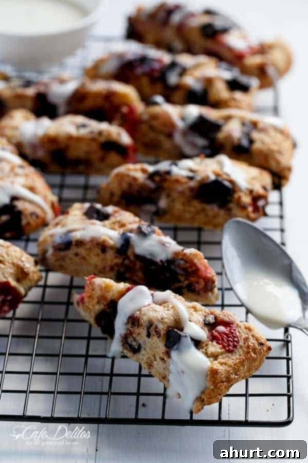 Mixed Berry and Chocolate Chunk Buttermilk Scones with a Cream Cheese Glaze pieces on a cooling rack