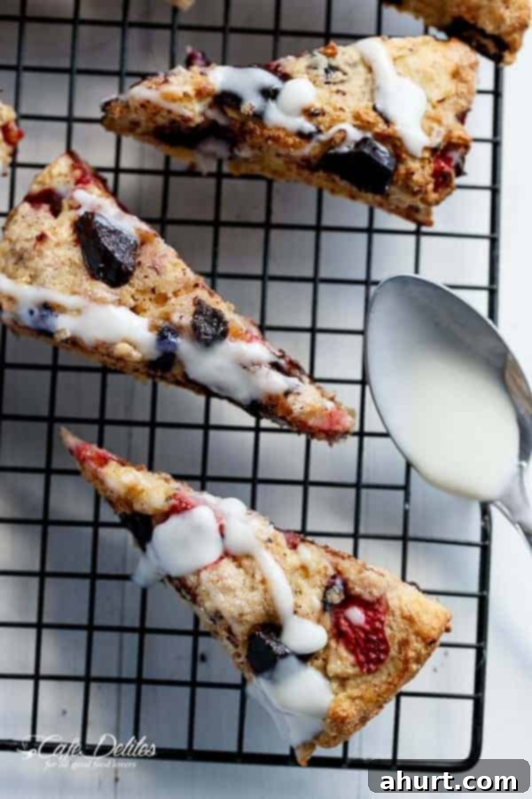 Mixed Berry and Chocolate Chunk Buttermilk Scones with a Cream Cheese Glaze on a cooling rack