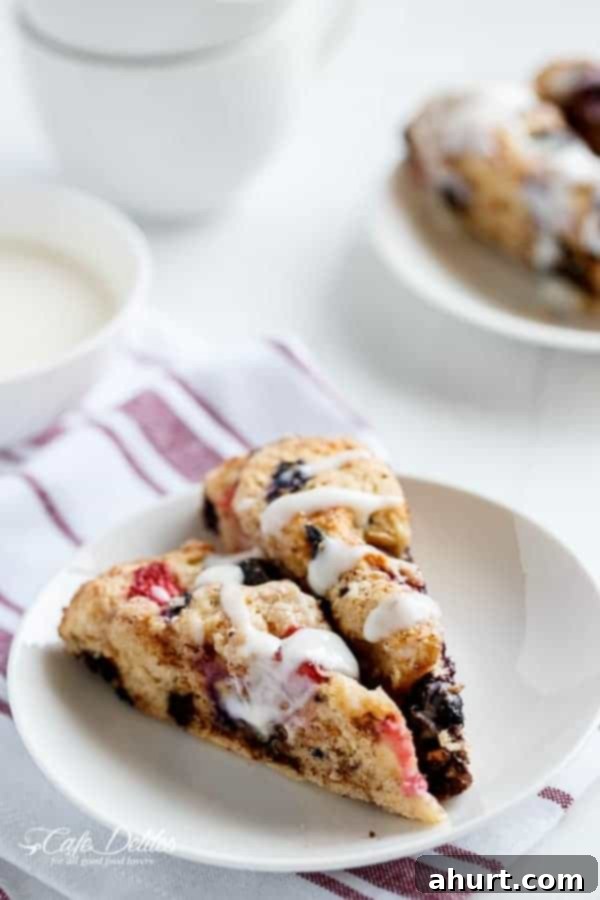 Mixed Berry and Chocolate Chunk Buttermilk Scones with a Cream Cheese Glaze pieces on a plate