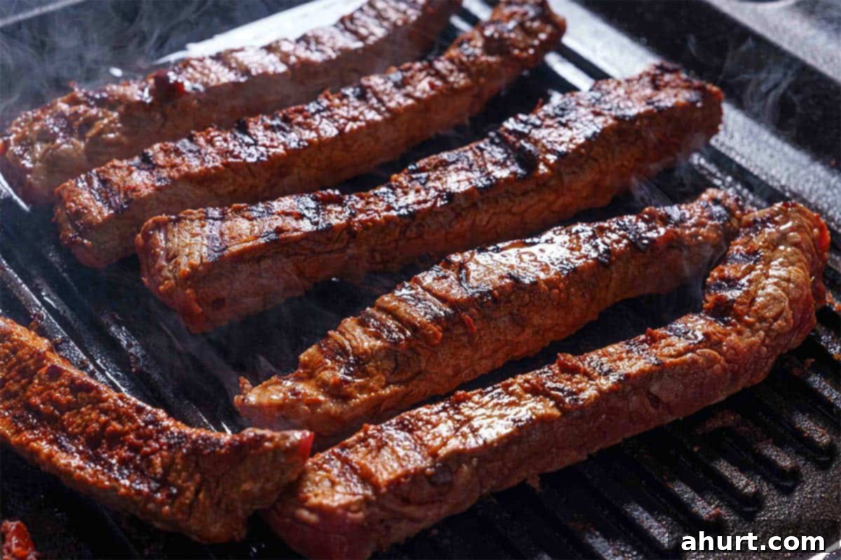 Savory Chipotle Carne Asada Pull Apart Loaf 4 Steak strips being cooked on a grill until brown.