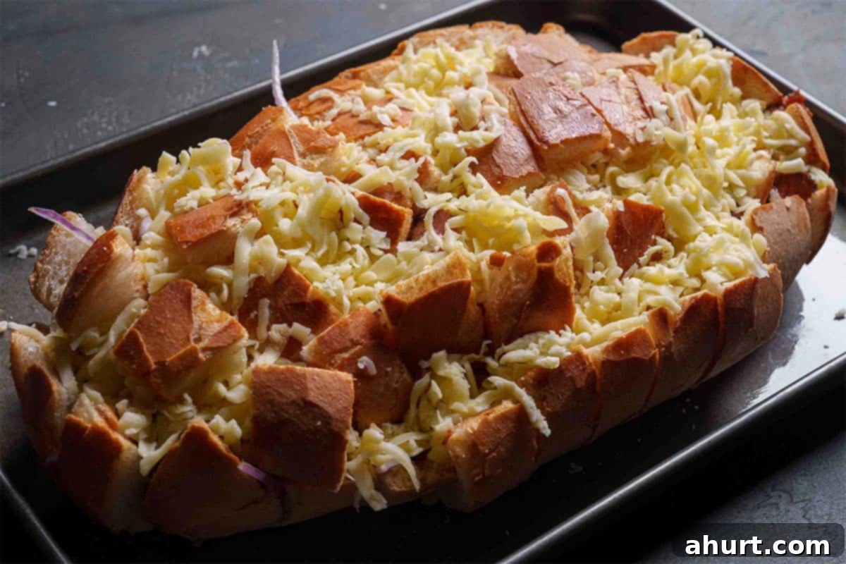 Savory Chipotle Carne Asada Pull Apart Loaf 7 Sourdough bread being stuffed with cheese, onions, and steak pieces into the crevices.