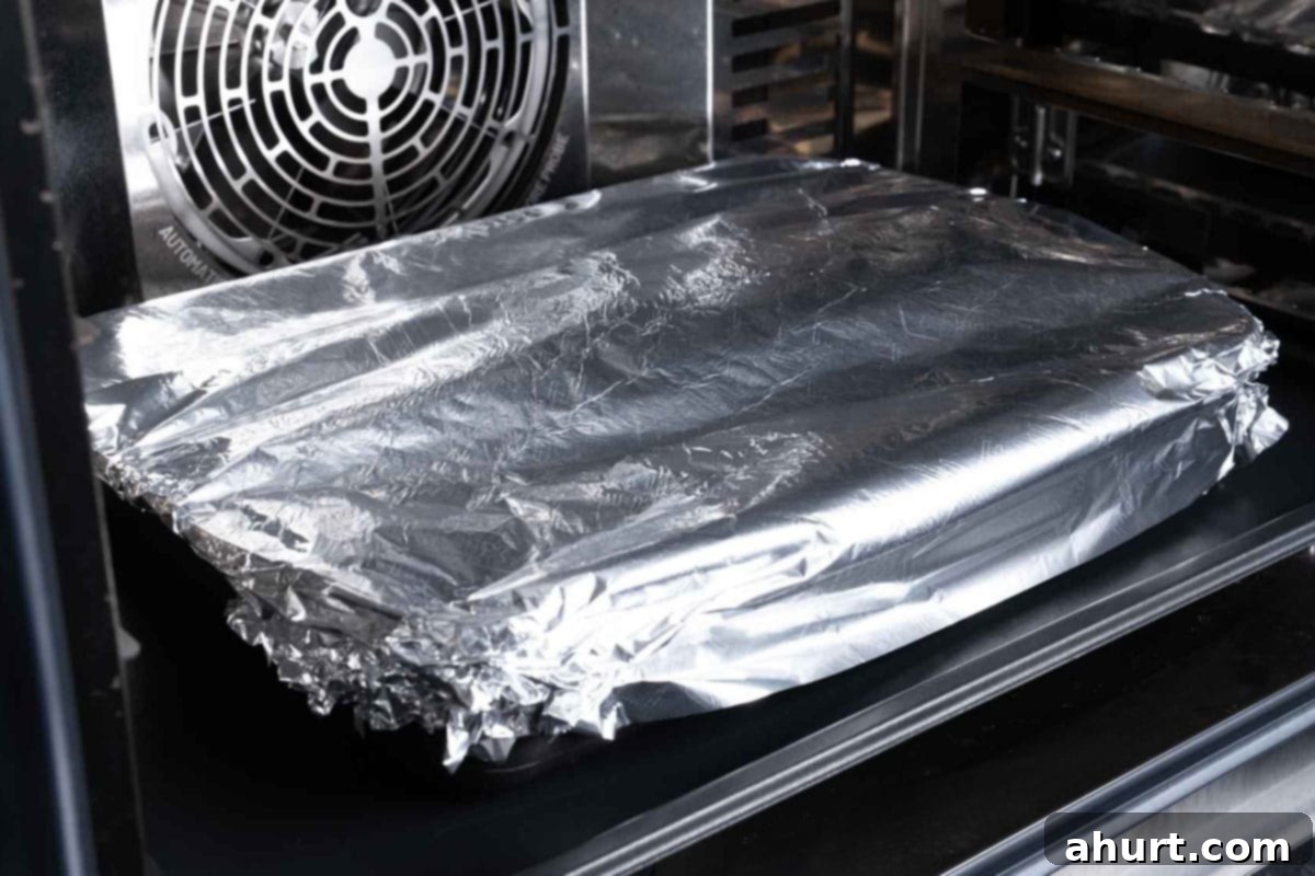 Savory Chipotle Carne Asada Pull Apart Loaf 8 Bread being covered with foil and baked until the cheese has melted.