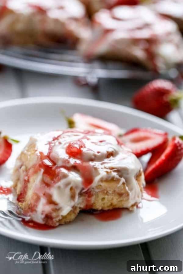Side view of fluffy No Yeast Strawberries And Cream Cinnamon Rolls with pink frosting