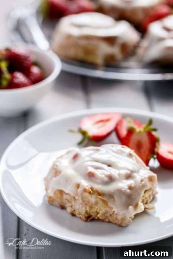 A single piece of No Yeast Strawberries And Cream Cinnamon Rolls on a white plate