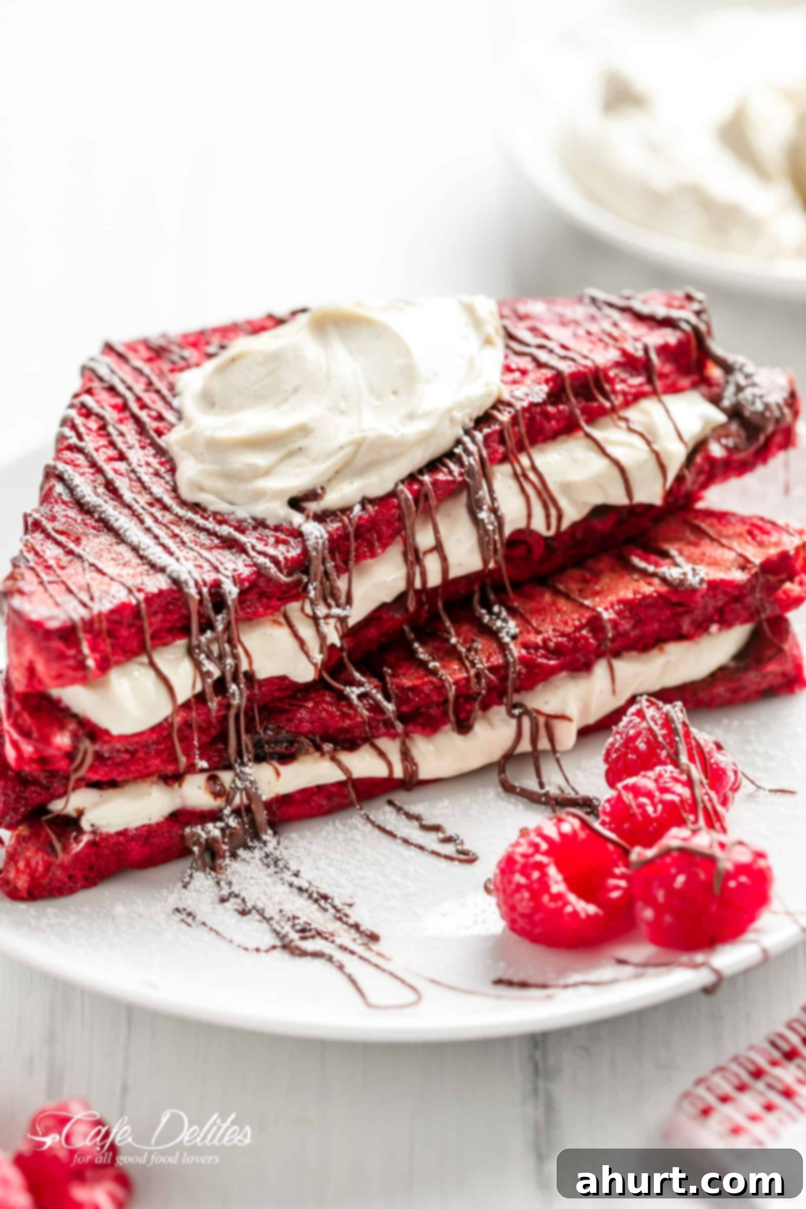 A final close-up of a perfectly prepared Red Velvet French Toast Cheesecake on a plate, garnished with fresh berries and powdered sugar