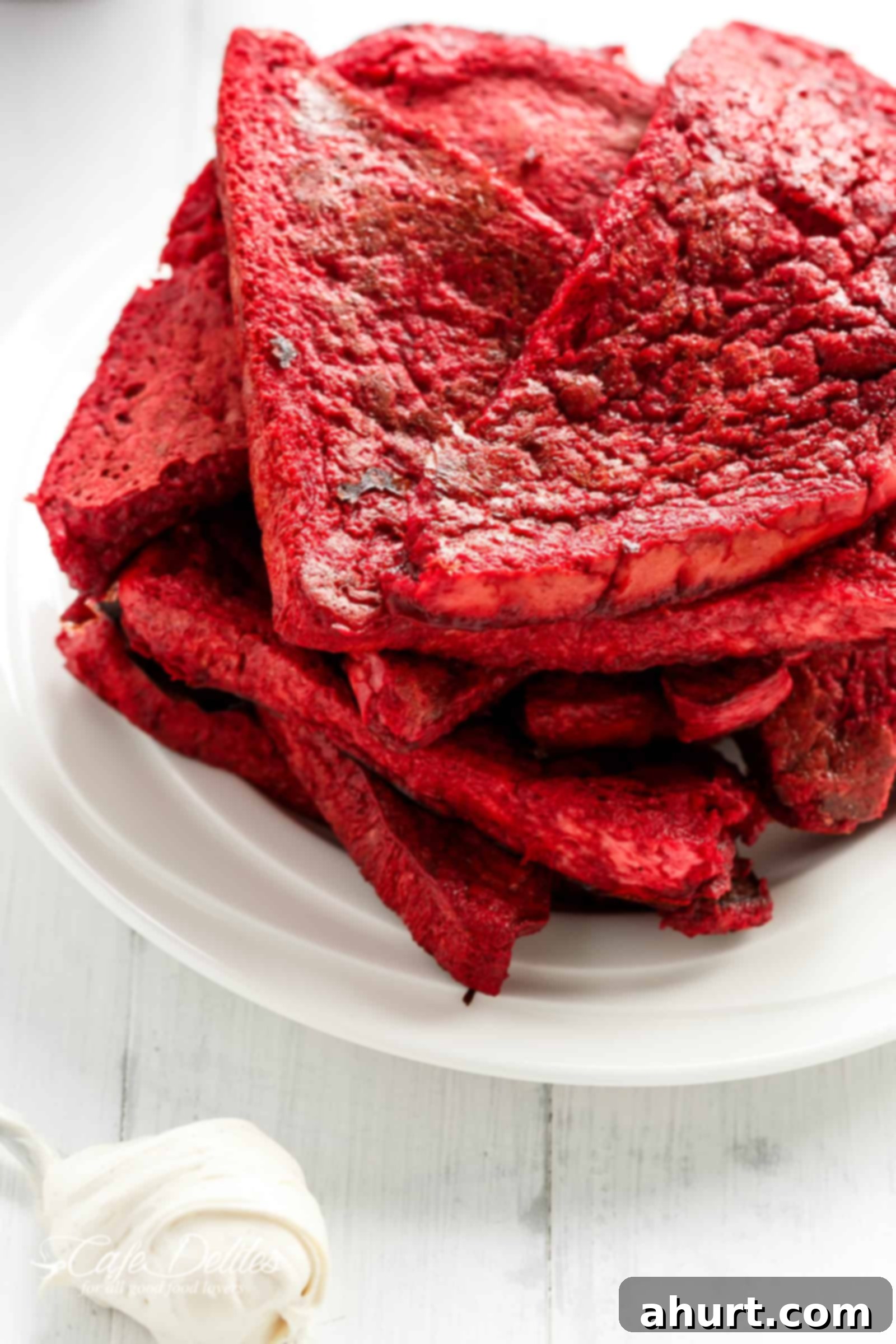 Multiple Red Velvet French Toast Cheesecake sandwiches stacked neatly on a white plate