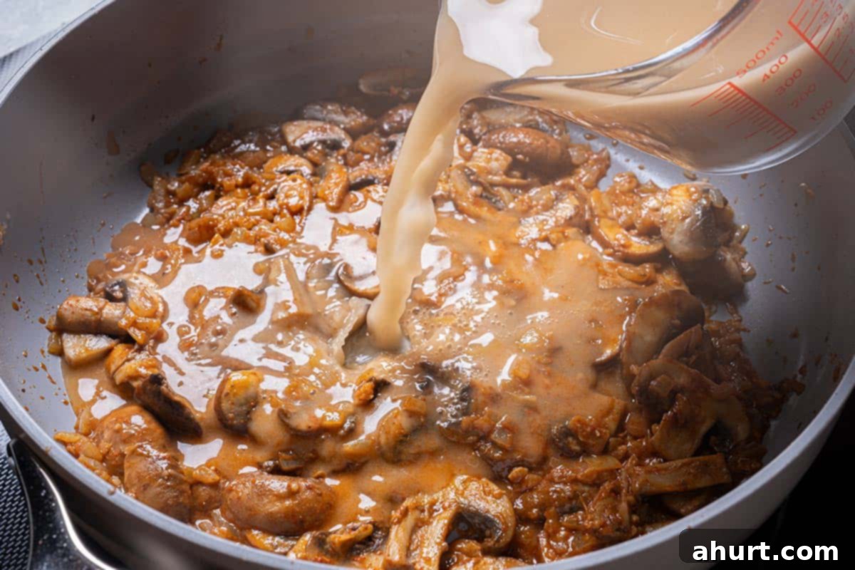 Velvety Beef Stroganoff with Earthy Mushrooms 8 A mixture of beef broth, flour, and Worcestershire sauce being added to the pan with simmering vegetables and wine.