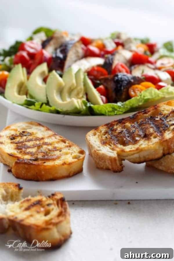 Side view image of Grilled Balsamic Chicken and Avocado Bruschetta Salad and bread pieces 
