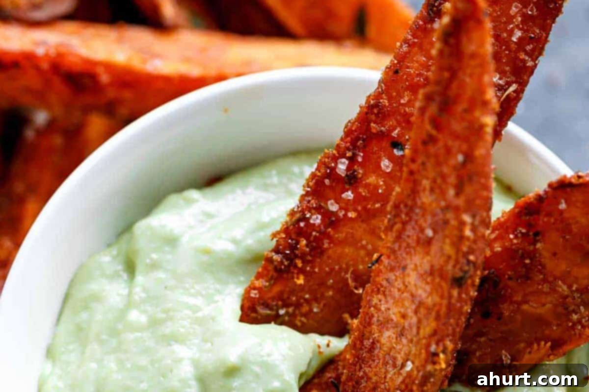Golden Crispy Sweet Potato Wedges with Creamy Garlic Avocado Aioli 11 Close-up shot of Crispy Sweet Potato Wedges with a side of creamy Garlic Avocado Aioli, ready to be served.