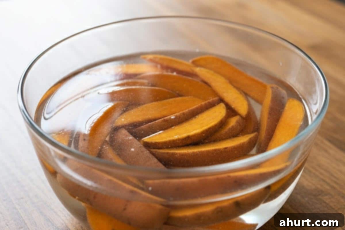 Golden Crispy Sweet Potato Wedges with Creamy Garlic Avocado Aioli 4 Sweet potato wedges soaking in a large bowl of cold water to remove excess starch.