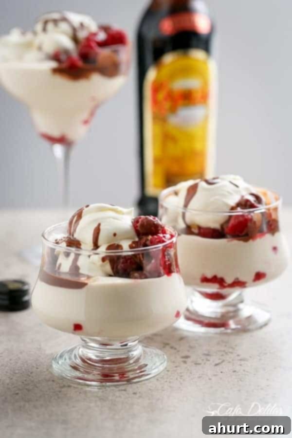 Decadent Kahlua Raspberry Cheesecake Parfaits 2 Two glasses of Creamy Kahlua Raspberry Cheesecake Parfaits, showing distinct layers of cream, raspberries, and chocolate drizzle.