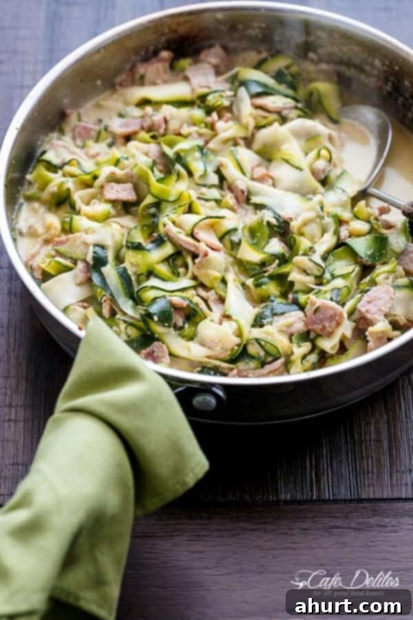 Zoodle Carbonara 3 Zucchini (Zettuccine) Carbonara simmering in a large skillet, showing the glossy, creamy sauce coating the zucchini ribbons and bacon pieces.