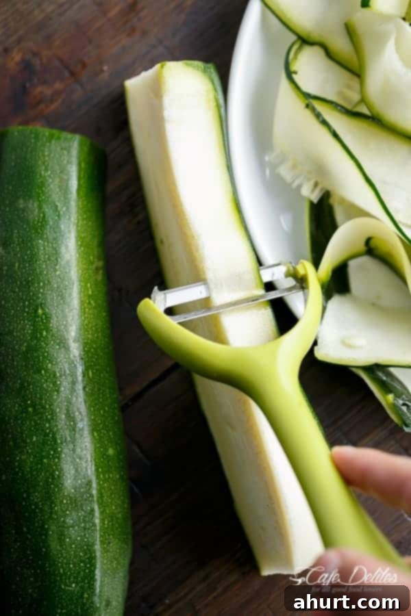 Zoodle Carbonara 4 Close-up of freshly peeled zucchini ribbons, neatly stacked, showcasing their natural green color and uniform width, ready for cooking.